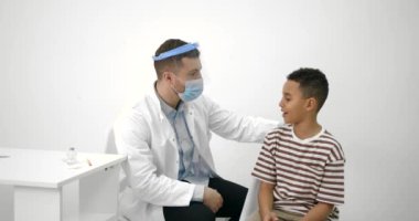 Erkek çocuk doktoru siyahi bir çocuğa aşı yapıyor.