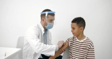 Erkek çocuk doktoru siyahi bir çocuğa aşı yapıyor.