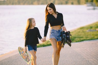 Anne ve kızı parkta kayarken eğleniyorlar.