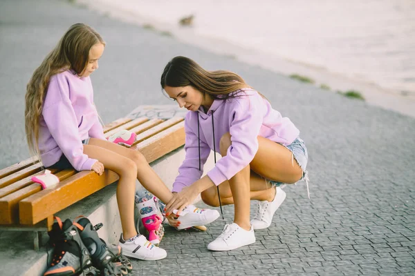 Madre aiuta la figlia a vestire i rulli al parco — Foto Stock