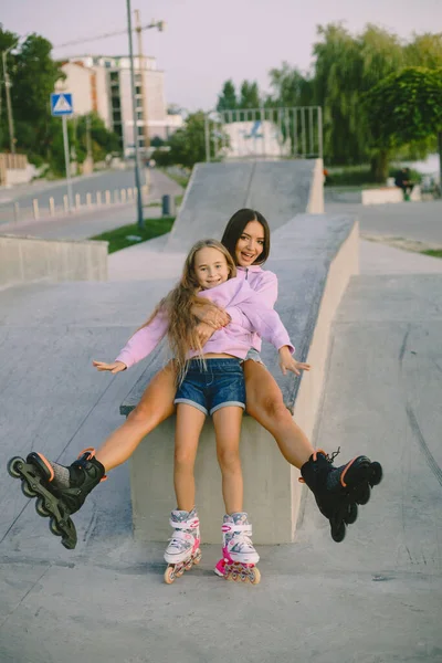 Mother with daughter rollerskating in park with lake — Zdjęcie stockowe