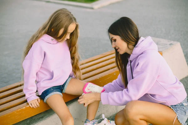 Mother helping daughter to dress rollers at park — Stock fotografie