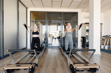 İki genç hamile kadın özel bir ekipman üzerinde alıştırma yapıyor.