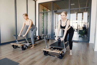 İki genç hamile kadın özel bir ekipman üzerinde alıştırma yapıyor.