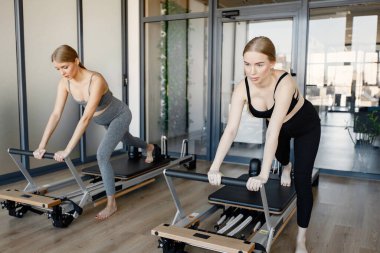 İki genç hamile kadın özel bir ekipman üzerinde alıştırma yapıyor.