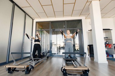 İki genç hamile kadın özel bir ekipman üzerinde alıştırma yapıyor.