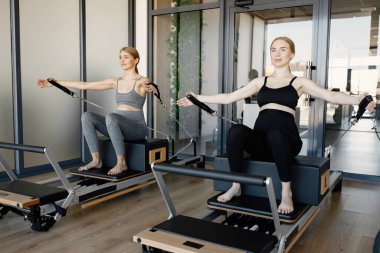 İki genç hamile kadın özel bir ekipman üzerinde alıştırma yapıyor.