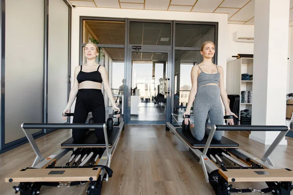 İki genç hamile kadın özel bir ekipman üzerinde alıştırma yapıyor.