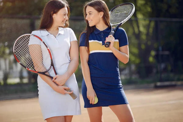 Duas jogadoras de tênis em um campo de tênis posando para uma foto — Fotografia de Stock