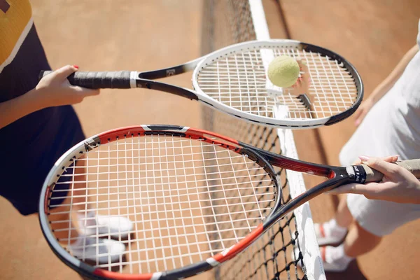 Cropped photo of two rackets and ball in hands of female tennis players — Stockfoto