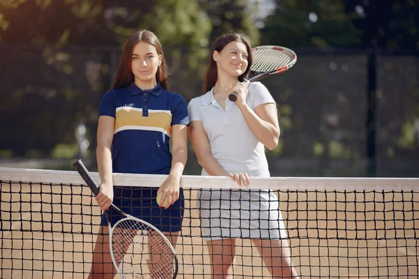 Two female tennis players on a tennis court posing for a photo — Stock fotografie