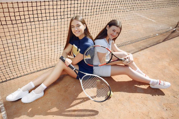 Dvě hráčky tenisu sedící na tenisovém kurtu pózují pro focení — Stock fotografie
