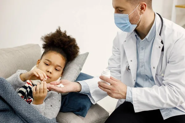 Male pediatrician give a medicines for sick little black girl — Stockfoto