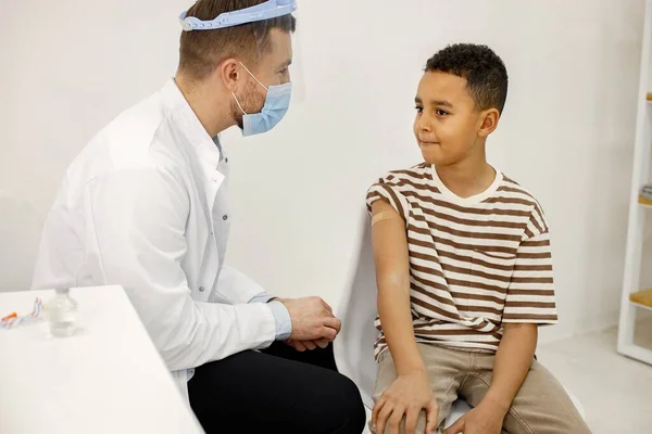 Male doctor stick a band-aid to a boy after a vaccination — Zdjęcie stockowe