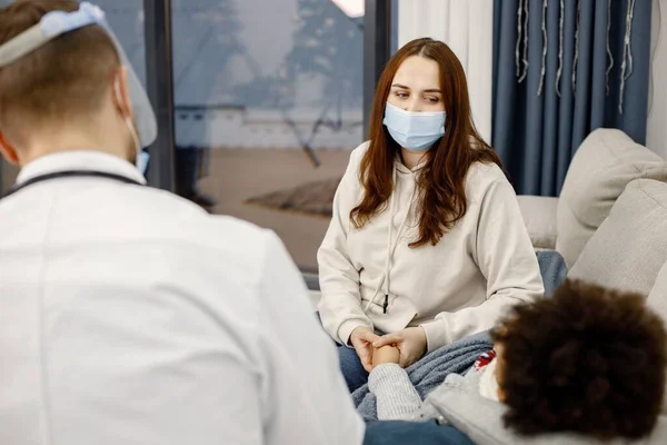 Focus on a mother talking with male pediatrician about her sick little girl — Foto de Stock