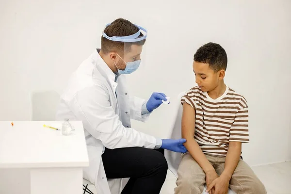 Male doctor stick a band-aid to a boy after a vaccination — Zdjęcie stockowe