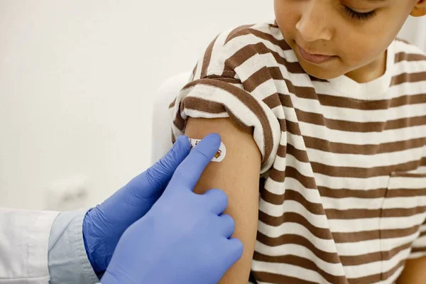 Gewassen foto van mannelijke arts plakken een pleister aan een jongen na een vaccinatie — Stockfoto