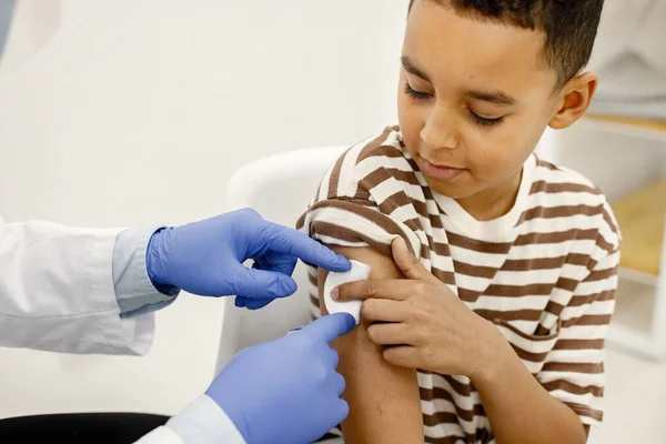 Mannelijke arts houdt een katoen op een jongens schouders na een vaccinatie — Stockfoto