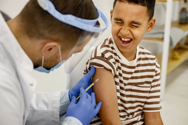 Male doctor doing a vaccination to a multiracional boy — Zdjęcie stockowe