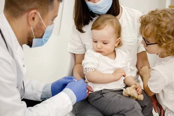Männlicher Arzt klebt einem Jungen nach einer Impfung ein Pflaster an — Stockfoto