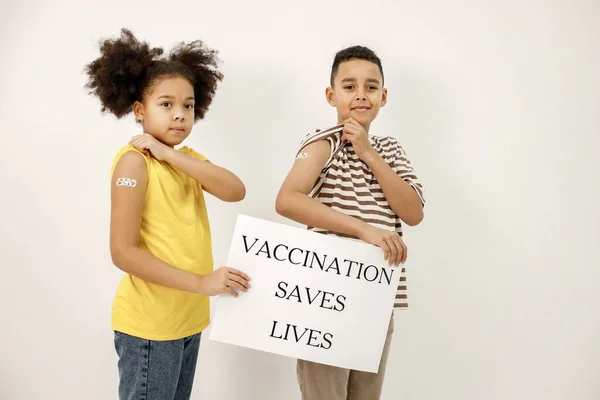 백신 접종 이 생명을 구해 준 포스터를 들고 있는 두 명의 다 인종 어린이 — 스톡 사진