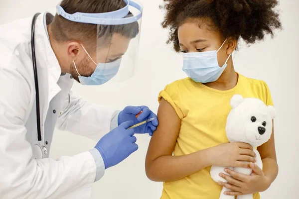 Чоловік-лікар робить вакцинацію чорній дівчині ізольовано на білому фоні — стокове фото