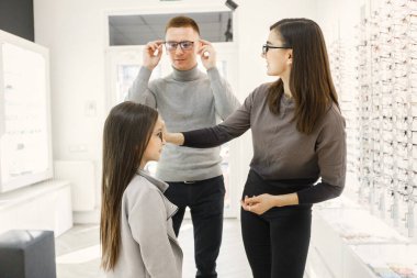 Optimetrist optik mağazasında ailenin gözlük seçmesine yardım ediyor