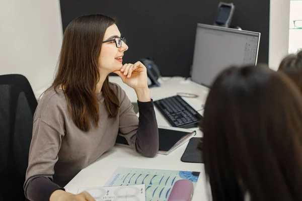 Professional female optician sitting at the table and working — Stock Fotó