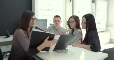 Parents with cute daughter try on glasses in a modern optics store