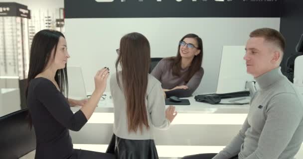 Γονείς με χαριτωμένη κόρη δοκιμάζουν γυαλιά σε ένα σύγχρονο κατάστημα οπτικών — Αρχείο Βίντεο