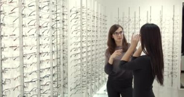 Woman chooses glasses with a consultant at opticians