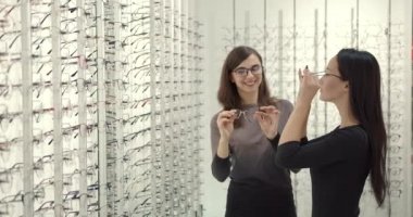 Woman chooses glasses with a consultant at opticians