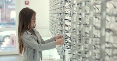 Modern parlak optik mağazasının vitrininde gözlüklü genç bir kız..