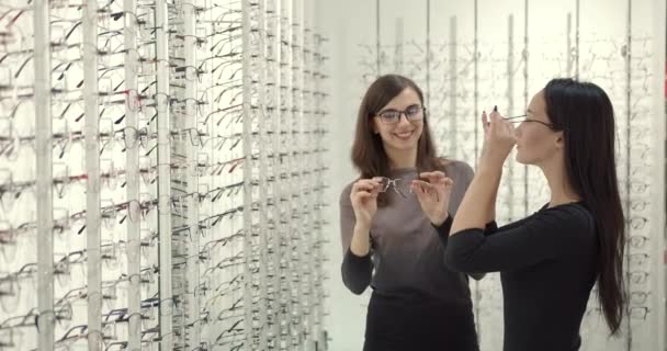 Γυναίκα επιλέγει γυαλιά με έναν σύμβουλο σε οπτικούς — Αρχείο Βίντεο