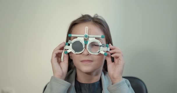 Schoolgirl girl in a bright modern optometrists office — Video