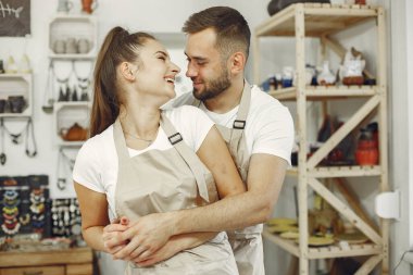 Young couple at standing in pottery with ceramic dishes