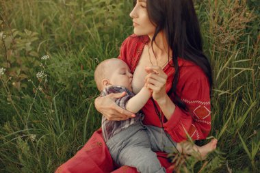 Kadın battaniyeye oturmuş oğlunu emziriyor.