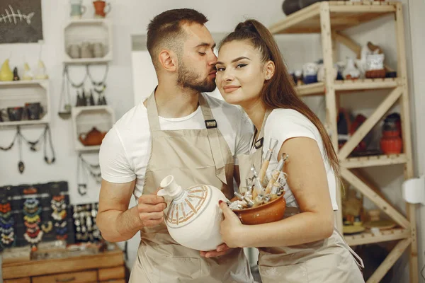 Young couple at standing in pottery with ceramic dishes — Stok fotoğraf