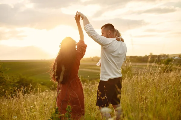 Söt familj som leker på ett sommarfält — Stockfoto