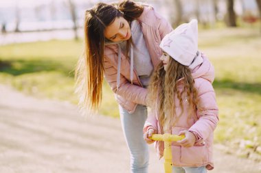 Anne ve kızı bahar parkında kayıyorlar.