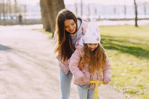 Mother with daughter in a spring park with skate — Stock Photo, Image