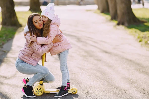 Mother with daughter in a spring park with skate — Stock Photo, Image