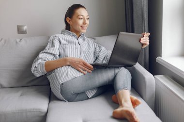 Kız evde oturuyor ve bilgisayarı kullanıyor.