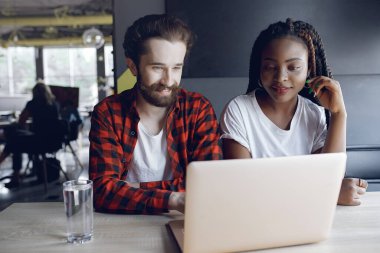 Birlikte çalışan gençler dizüstü bilgisayarlarını kullanıyorlar.