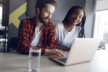 Birlikte çalışan gençler dizüstü bilgisayarlarını kullanıyorlar.