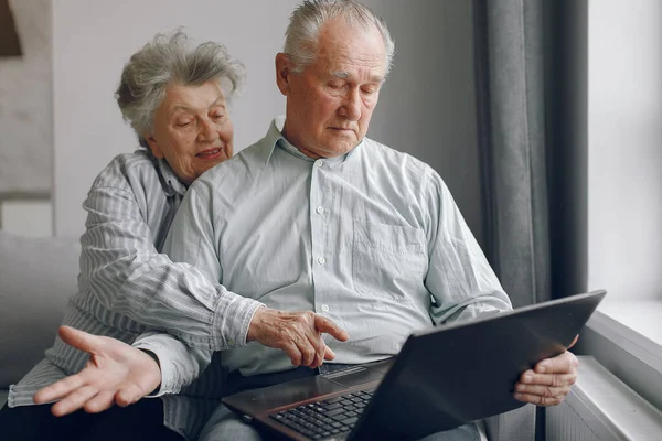 Элегантная пожилая пара сидит дома и пользуется ноутбуком — стоковое фото