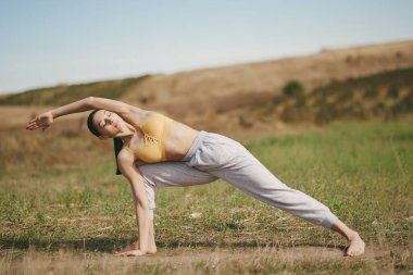 Gökyüzü arka planında eğitim alan güzel bir kız. Sarı bluzlu kadın. Bayan yoga yapıyor.
