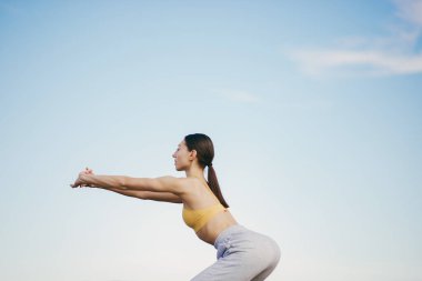 Gökyüzü arka planında eğitim alan güzel bir kız. Sarı bluzlu kadın. Bayan yoga yapıyor.