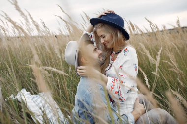 Buğday tarlasında birbirini seven bir çift. Erkek arkadaşlarıyla güzel bir sarışın. Battaniyenin üzerinde oturuyorlar.