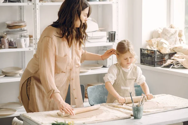 Kadın ve kız kil yoğuruyor. Aile, çömlekçilik atölyesindeki masada sanat ürünü yapıyor. Anne ve kızı..